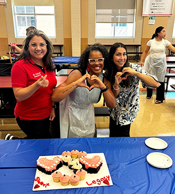 Three happy employees next to a cake