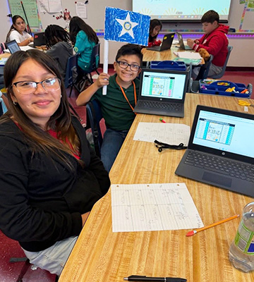 Happy students in the classroom with tablet computers on their desk