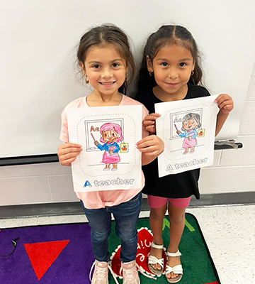 Two happy elementary school girls holding up their drawings