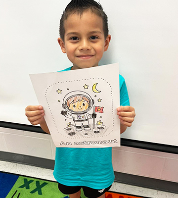 Male elementary student holding up his artwork