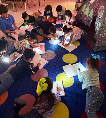 Group of elementary students drawing on the floor with flashlights