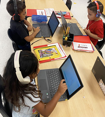Elementary students enjoying online learning activities on laptop computers