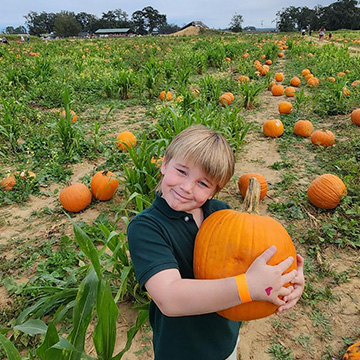 Students holding a pumpkin in a pumpkin patch