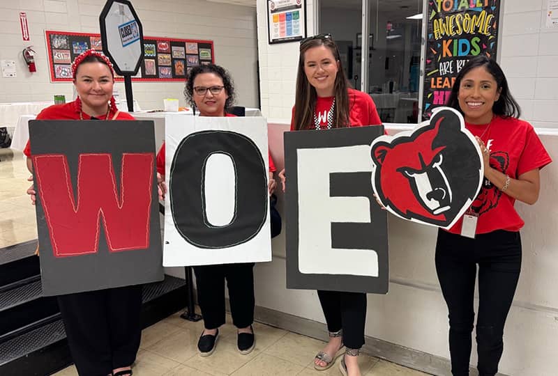 Happy students sitting at a blue table in the cafeteria