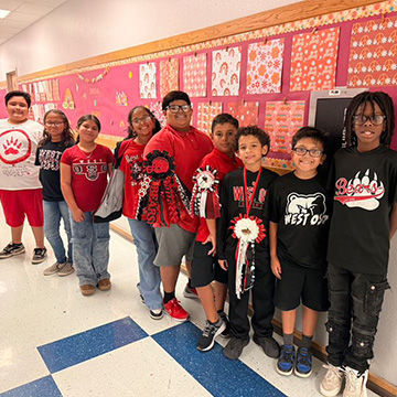 Nine students in the school hallway behind three award ribbons