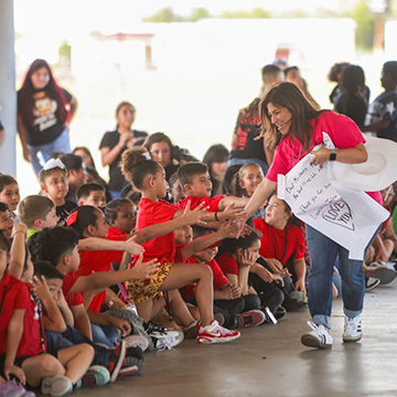 An adult giving high fives to students