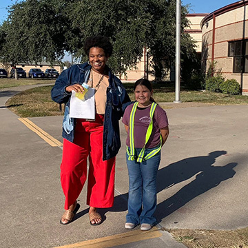An adult standing next to a student crossing guard