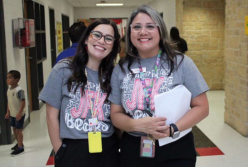 Two teachers smiling in the hallway
