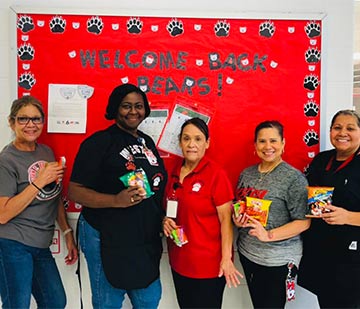 Teachers smiling and holding bags of candy