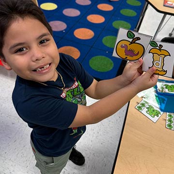 Student showing off the letter D for Dinosaur