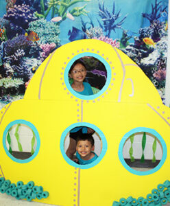 brother and sister looking through window holes of a submarine cutout