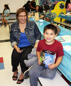 adult and student raffle winner smiling while holding prize