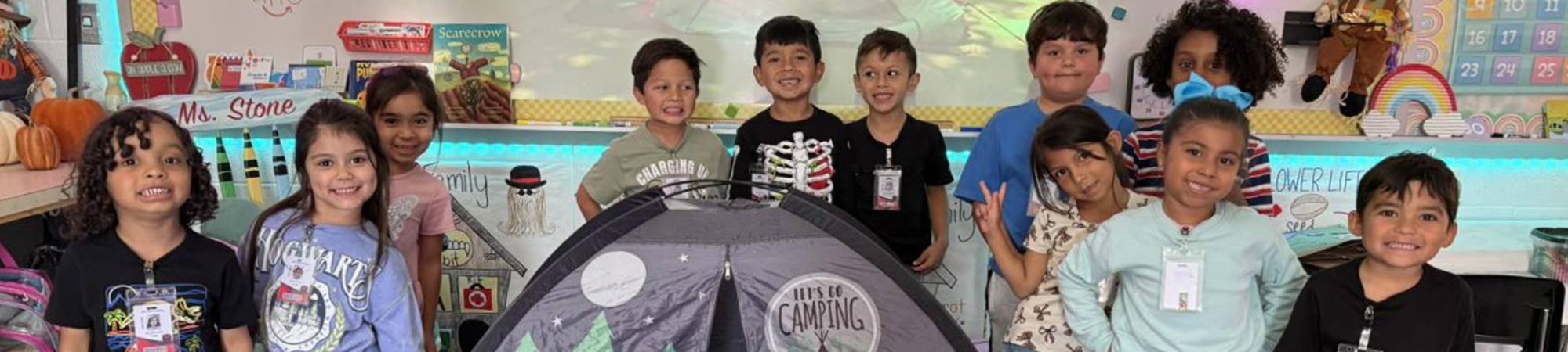 Students smiling together pretending to camp in class