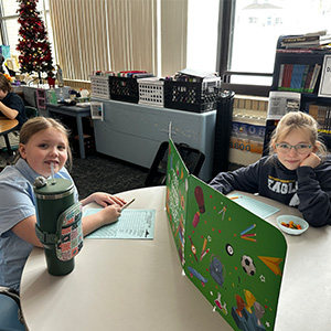 Students at a table with a divider between them