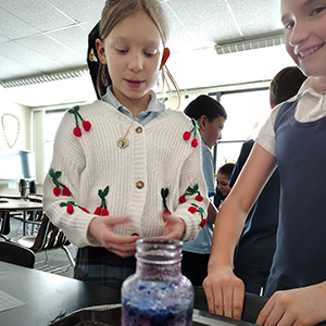Two students looking at something blue in a jar