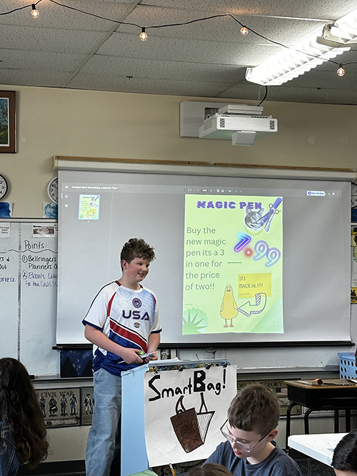 Sixth grade boy in USA t-shirt presenting his "Magic Pen" project to the class