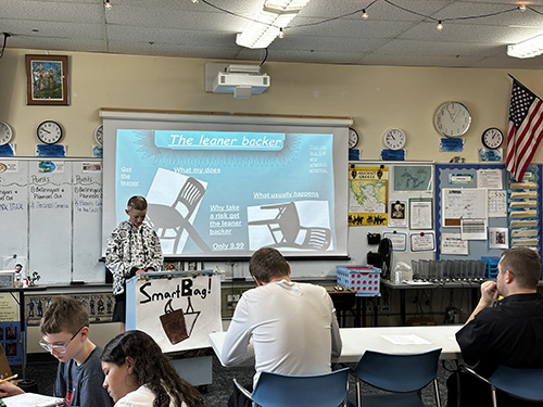 Student presenting his "the leaner backer" chair project