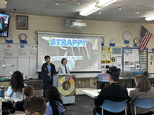Two students at the podium presenting their STRAPPY project