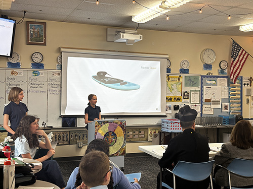 Student at a podium presenting her project on the projection screen