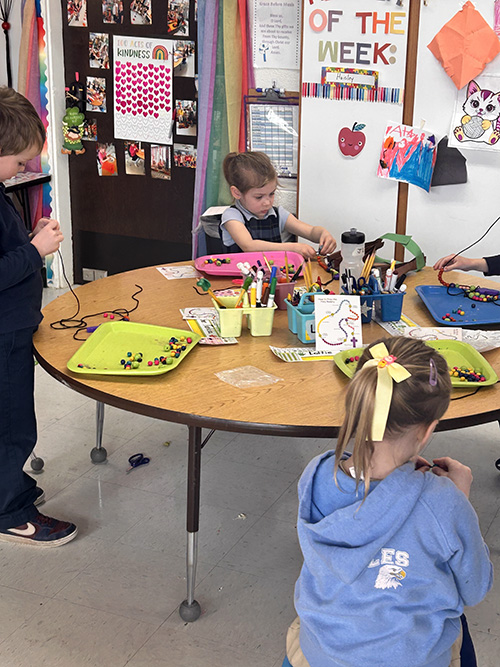 Group of students at a round table making their own Rosary beads