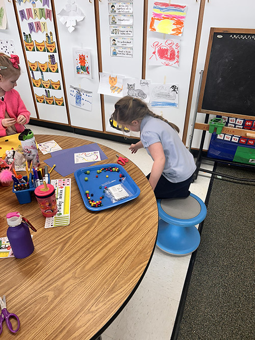 Kindergarten student making her own Rosary