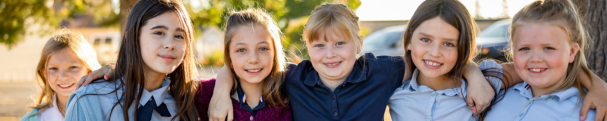 A group of smiling girls in their school uniform outside