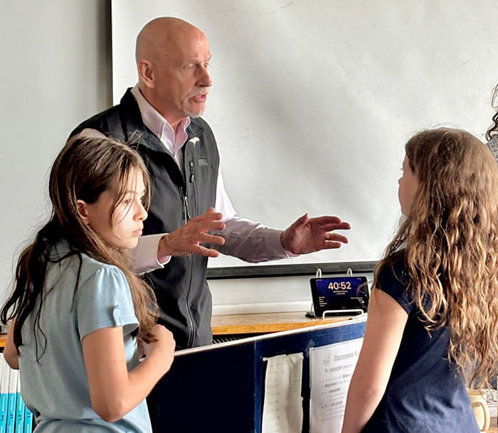 Guest speaker Karl Bohnak speaking to two fifth grade girls