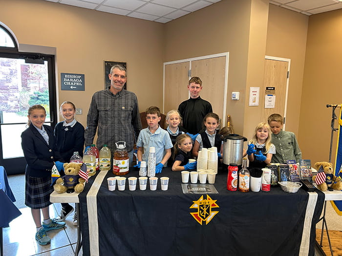 FMCA students with adult behind snack table at St. Peters Cathedral