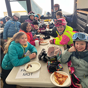 Students dressed in coats eating pizza