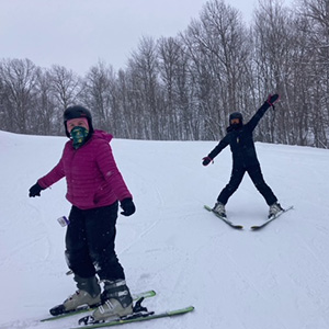 Students skiing downhill with arms spread out