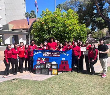 Group of students outside in red jackets holding up a banner
