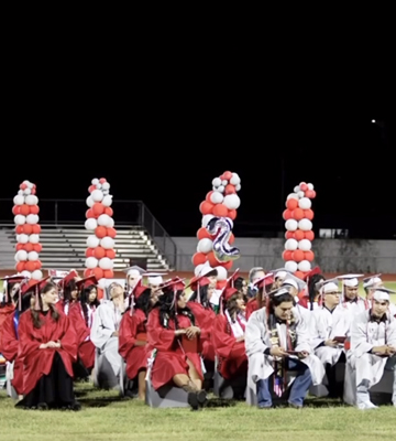 Students sitting during graduation ceremony on the football field
