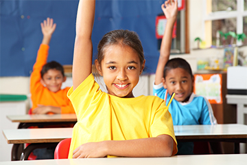 School children raising their hand in the classroom