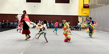 Students dressed in formal Indian attire and dancing with an adult leader