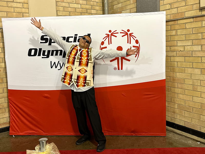 Student wearing banner in front of Special Olympics sign