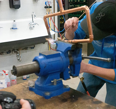 Student working on metal in a vise grip