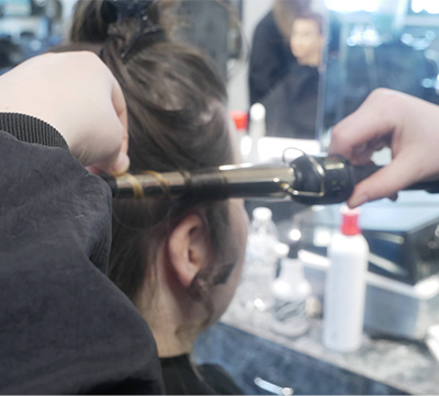 Student using a curling iron on someone's hair