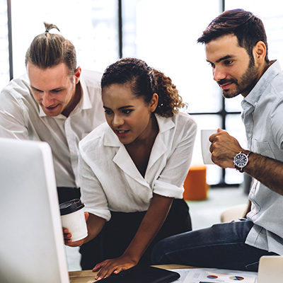 Three students looking at a laptop together