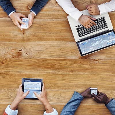 Four people looking on different types of devices