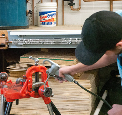A student adding oil to a piece of machinery that is in a vise grip