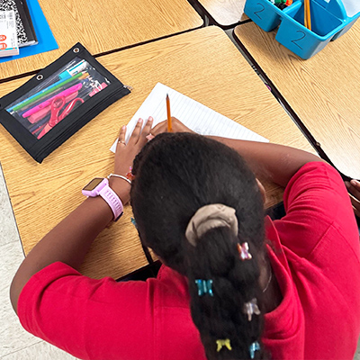 Student in red shirt working at her desk