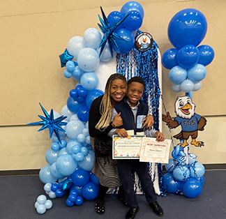 Proud student with parent under celebration balloons