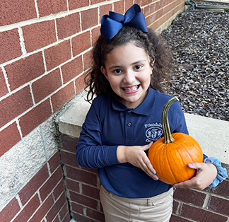 Little girl smiling with a pumpkin