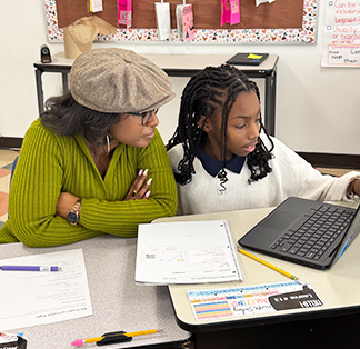 Teacher helping student with an assignment using a laptop