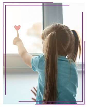 girl pointing to a heart on the window
