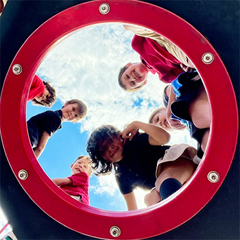 Elementary students looking through a playground circle