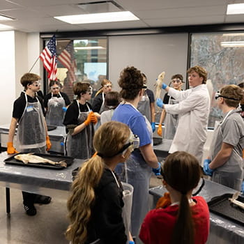 teacher holding up a fish while science students look on