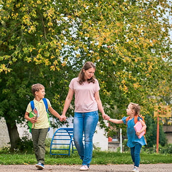 Mom walking in hand in hand with her children, walking to school