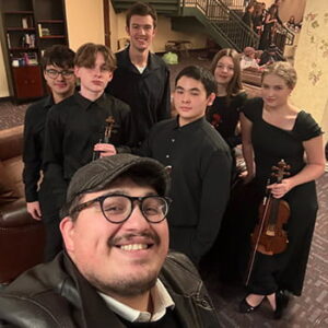 teacher standing with six students after an orchestra concert