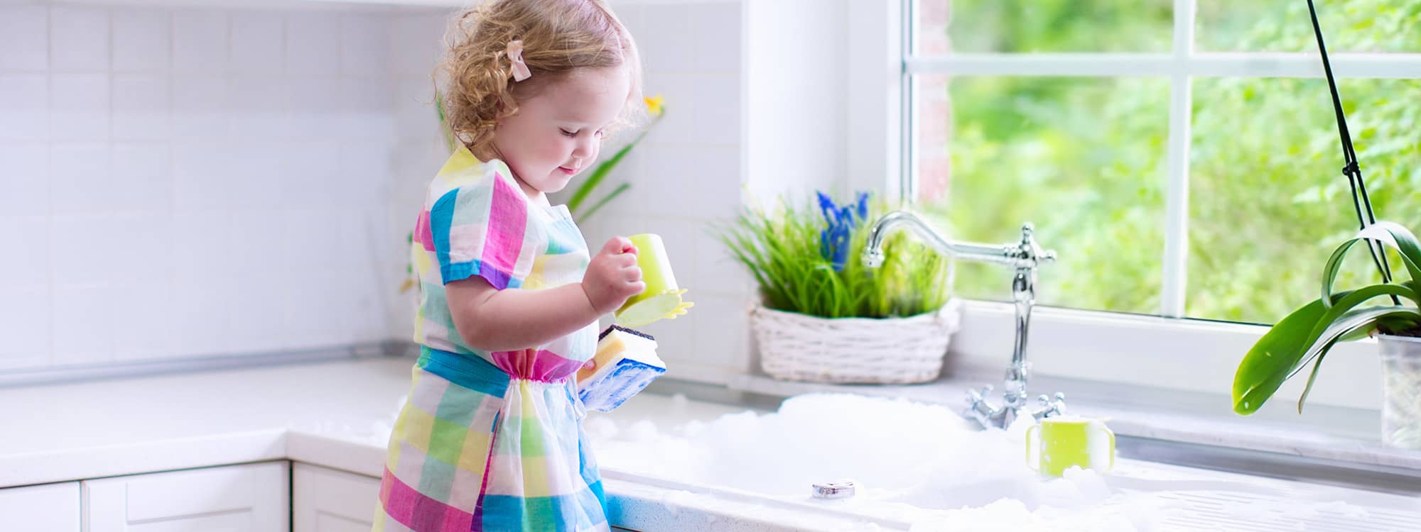 little girl washing dishes at the kitchen sink
